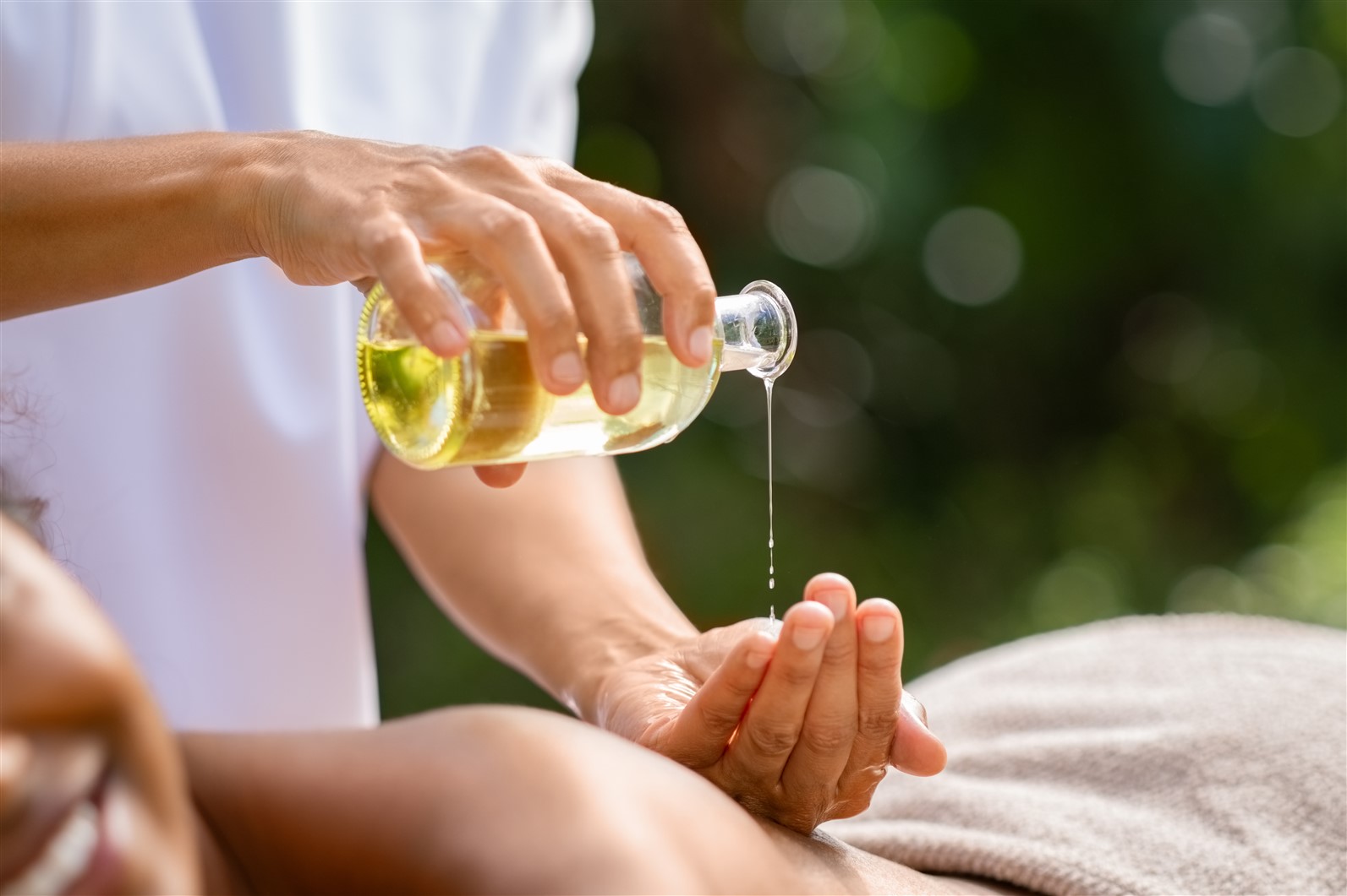 A therapist pouring hemp oil on a ladies back before a massage